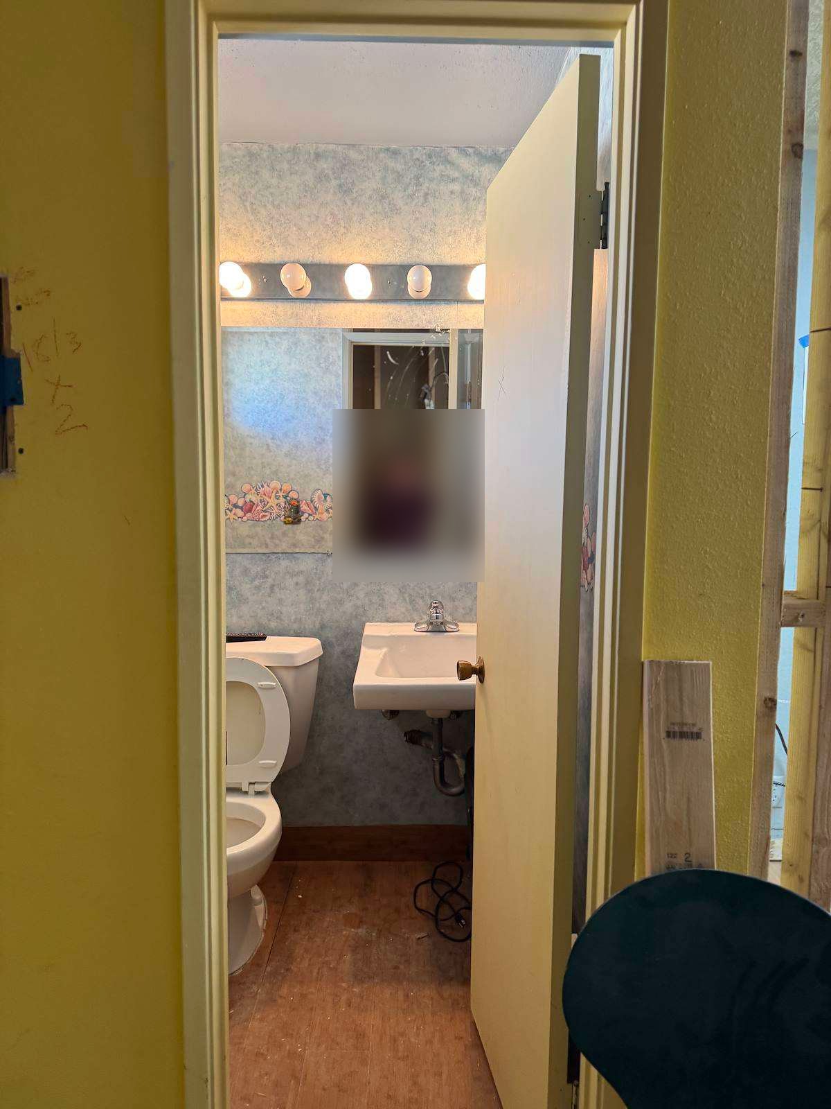 Smiles by Pai before: original restroom with faux-finish wallpaper, Hollywood vanity lights, and wall-mounted sink